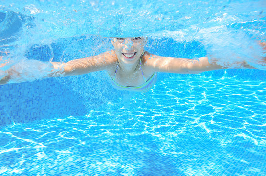 Kid swims in pool underwater, girl swimming and having fun