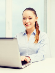 smiling businesswoman with laptop in office