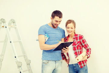 smiling couple with clipboard and wallpaper roll