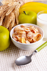 Sweet cornflakes in ceramic bowl, fruits and glass with milk