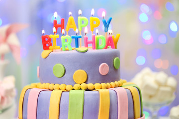 Delicious birthday cake on shiny light background
