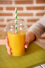 Female hand at table with fast food closed cup of orange juice