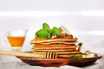Stack of pancakes with mint, walnuts and slices of banana