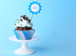 Delicious cupcake with inscription on blue background