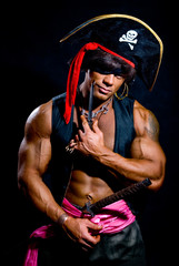 Portrait of a muscular pirate with a knife on a dark background.