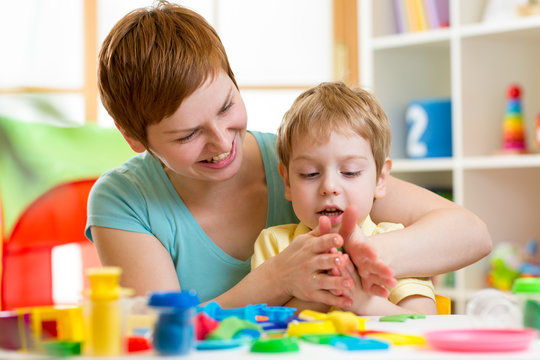 kid boy and mother playing colorful clay toy
