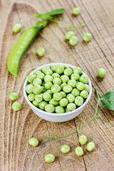 green split peas in a white cup on a rustic wooden background