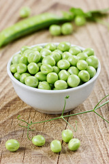 green split peas in a white cup on a rustic wooden background