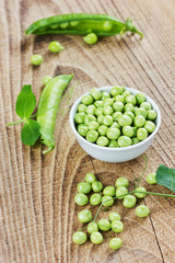 green split peas in a white cup on a rustic wooden background