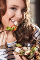 Young woman eating fresh vegetable salad