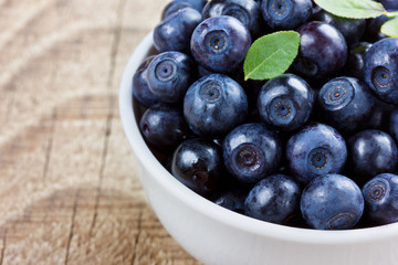 blueberries in the white bowl on a wood rustic background