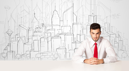 Businessman sitting at the white table with hand drawn buildings