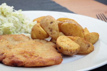 Wiener schnitzel with fried potato wedges and cabbage salad.