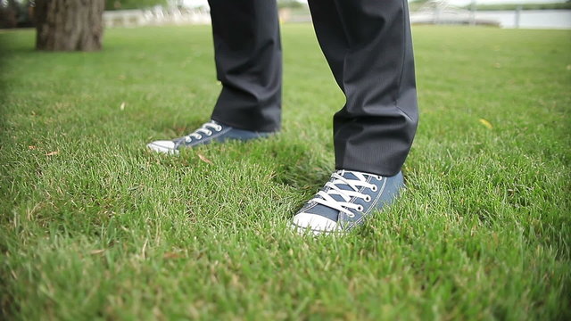 close up, the feet  in sneakers stand down on the grass