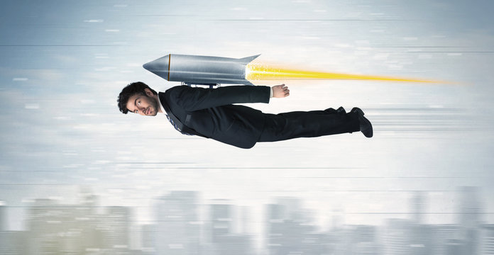 Superhero business man flying with jet pack rocket above the cit