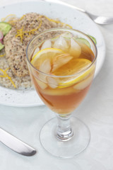 Iced tea with lemon next to plate full of food.