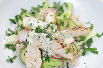 Slices of chicken breast over green salad and barley.