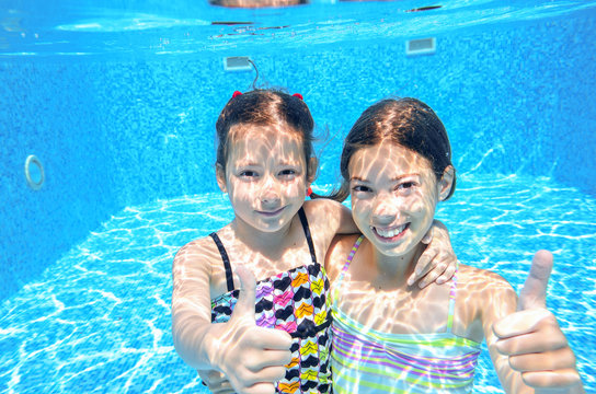 Kids swim in pool underwater, girls swimming and having fun
