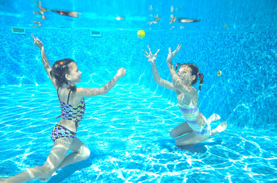 Kids swim in pool underwater, girls swimming and having fun