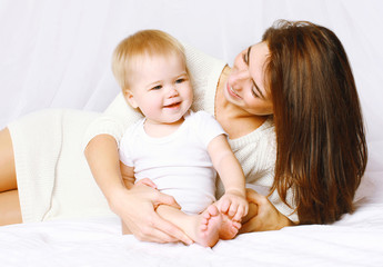 Fototapeta na wymiar Happy mom and baby having fun in bed at home, life moment