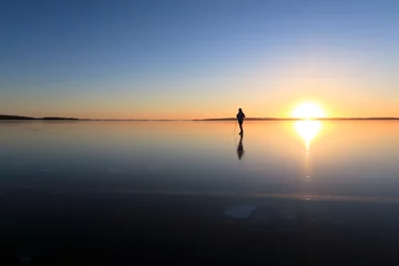 Foto auf Acrylglas Ice skating on lake Malaren, Sweden, at sunset. © pownibe