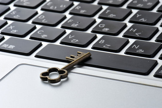 パソコンのキーボードと小さな鍵の写真,個人情報保護のイメージ