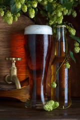 Glass of beer with barrel, bottle and fresh hops still-life