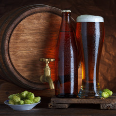 Bottled and unbottled beer glass with vintage old barrel
