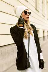 Glamorous blonde standing at the wall. Urban fashion black and w