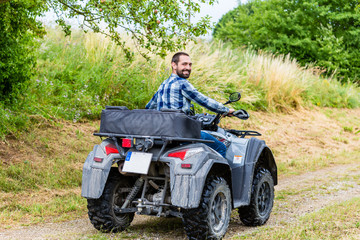 Fototapeta na wymiar Mann fährt Off-Road mit Quad ATV durch Gelände 