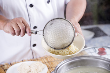 Fototapeta premium Chef putting cooked Noodle to the bowl