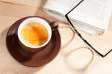 Eine Tasse Kaffee mit Zeitung und Brille