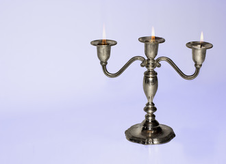 Silver candlestick holding three almost burnt-out candles