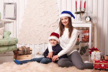 Obraz na płótnie Canvas Little boy with mom posing in Christmas interior