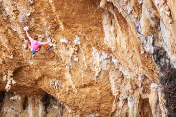 Young female rock climber on overhanging cliff