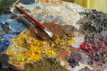 Focused trowel and brush on oil paint palette