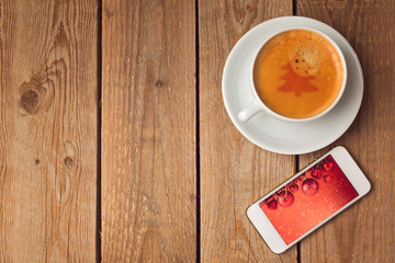 Coffee cup and smartphone with christmas picture.