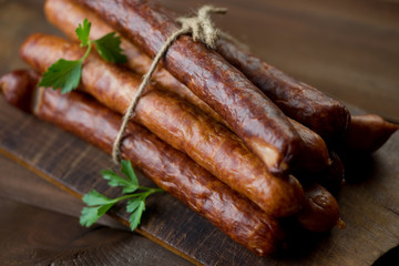 Stack of smoked sausages on a rustic chopping board, close-up