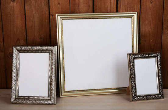 Photo frames on wooden surface and wooden wall background