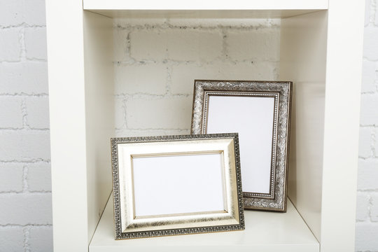 Photo frames on shelf on brick wall background