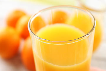 Glass of orange juice and oranges on wooden table background