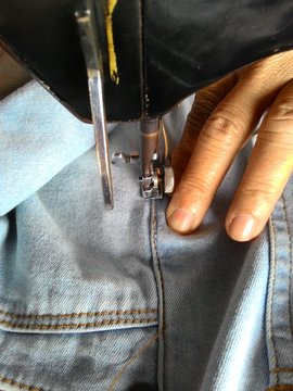 Close-up of old sewing needle with fingers Male to scrap denim.