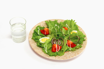 A vegetarian salad and a glass of water, isolated on white
