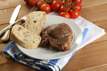 Roasted meat and vegetables on plate, on wooden table