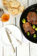 Roasted meat and vegetables on pan, on wooden table background