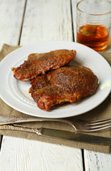 Roasted meat on plate, on wooden table background
