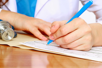 A female doctor is fiiling a prescription - close-up