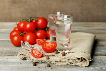 Glasses of ouzo and tomatoes on wooden table