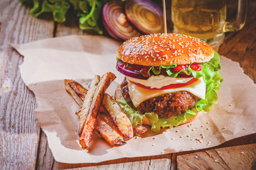 Delicious a burger and fries with a beer in the background onion
