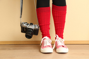 Girl in sneakers with retro photo camera in room